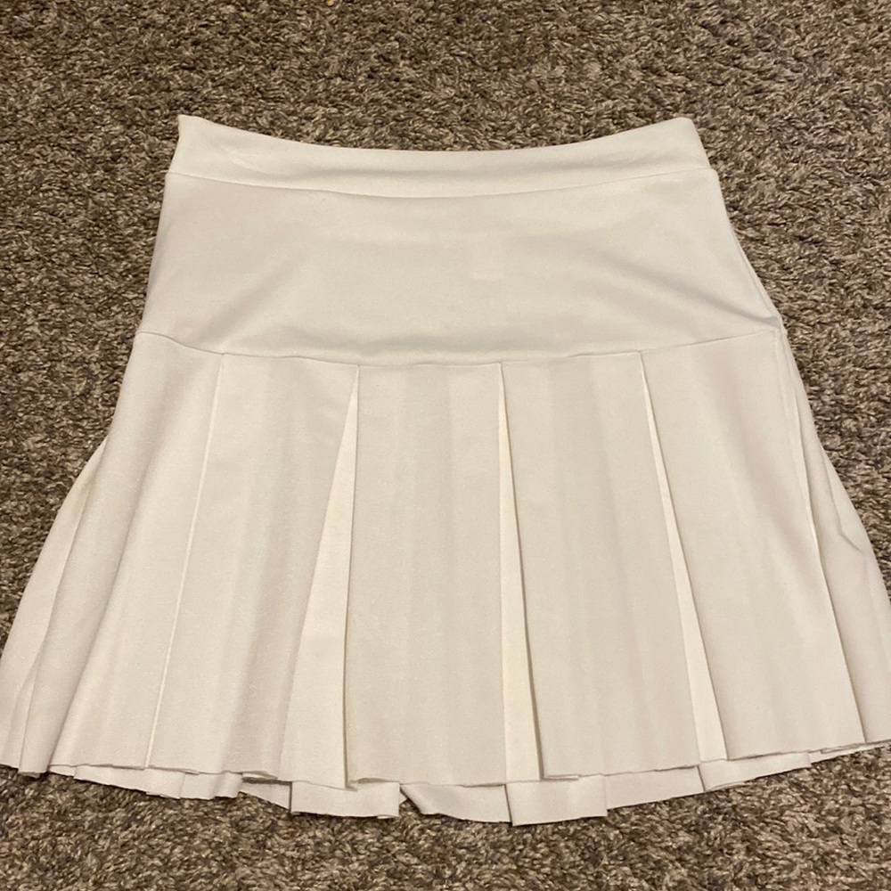 White tennis skirt with folded pattern and zipper on right side.